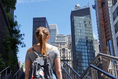 Low angle view of woman standing by railing in city