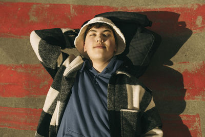 Directly above view of young man lying on floor with eyes closed during sunny day