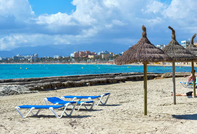 Chairs on beach by sea against sky