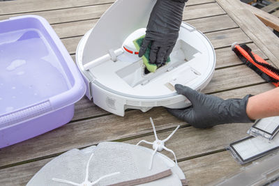 Woman washing a trash can in a robot vacuum cleaner, planned maintenance