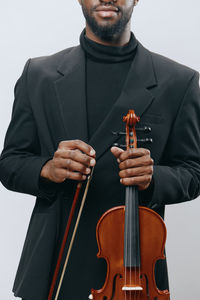 Midsection of man playing violin against white background