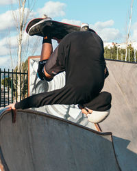 Rear view of man sitting on skateboard against sky