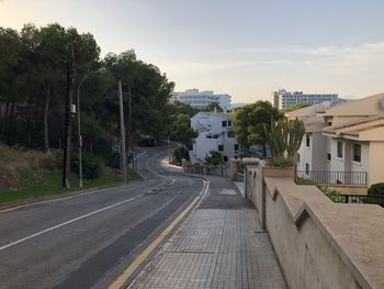 Road by buildings in city against sky