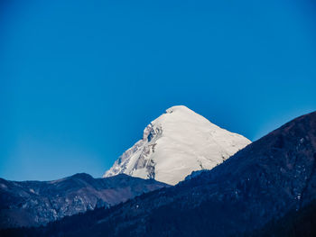 Low angle view of snowcapped mountain against blue sky