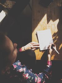 High angle view of woman writing on paper at table