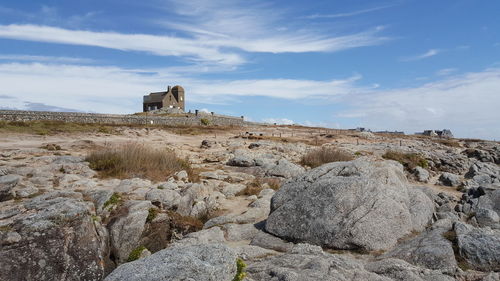 Old ruins on cliff against cloudy sky