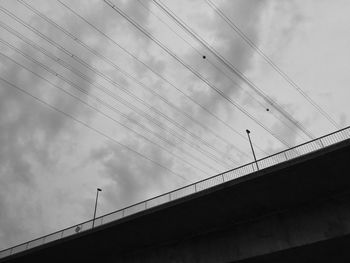 Low angle view of birds flying over bridge against sky