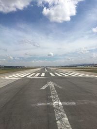 View of airport runway against cloudy sky