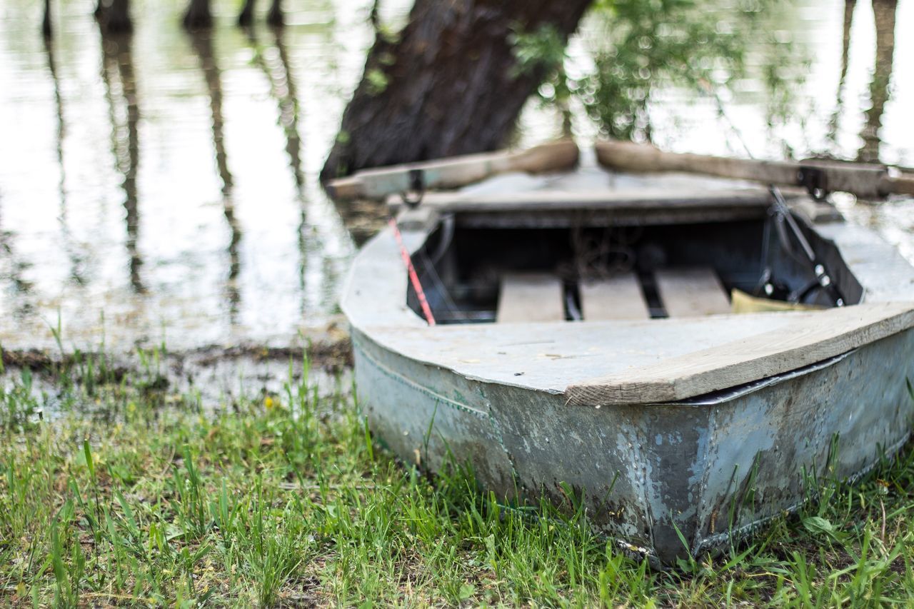 nautical vessel, boat, water, moored, transportation, mode of transport, abandoned, grass, wood - material, lake, old, damaged, tree, outdoors, day, nature, focus on foreground, lakeshore, tranquility, obsolete