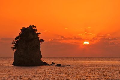 Scenic view of rock formation against sea at sunset