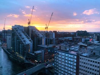 Modern buildings in city against sky during sunset