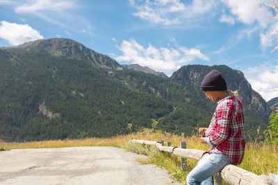 Rear view of woman standing on road against mountain