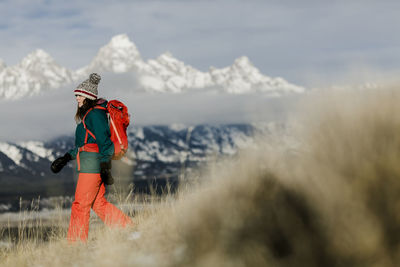 Side view of female hiker with backpack against snowcapped mountains