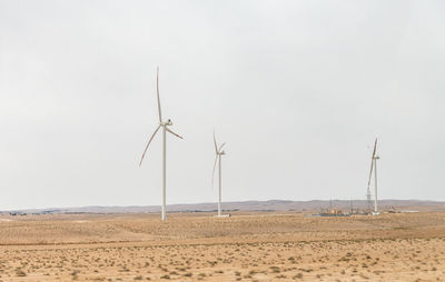 Windmills on field against clear sky