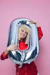 Portrait of woman holding gift against pink background