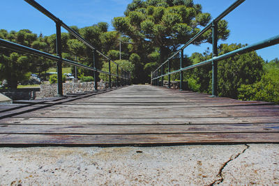 Footbridge amidst trees against sky