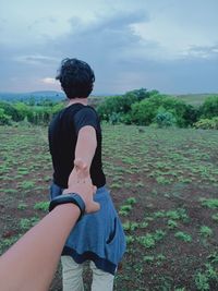 Rear view of man standing on field against sky