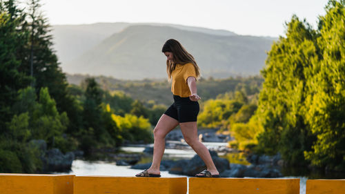 Side view of young woman standing on mountain