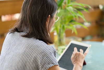 Senior asian woman using digital tablet to reading social media at home