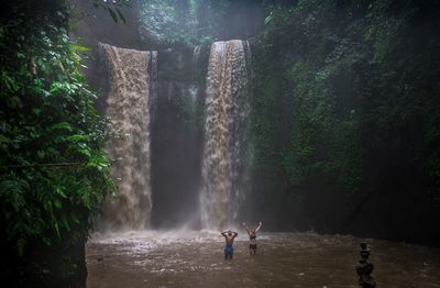 Friends enjoying against waterfall in rainforest