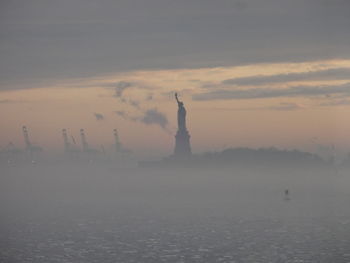 Silhouette statue of liberty in foggy weather during sunrise
