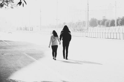 Rear view of friends walking on snow covered landscape