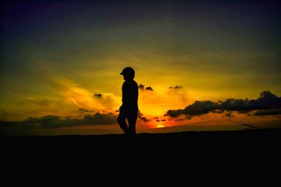 Silhouette man standing on landscape against orange sky