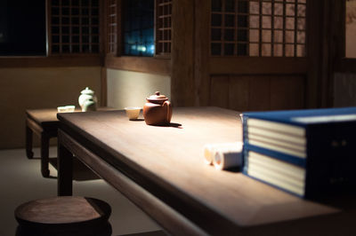 Teapot and books close up in dark room.