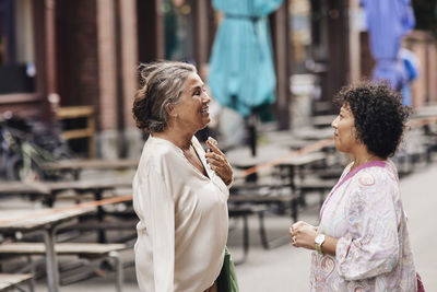 Smiling disabled woman talking with female friend while standing at street