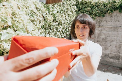 Surprised woman receiving package from delivery person