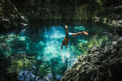 Full length of teenage boy jumping in pond