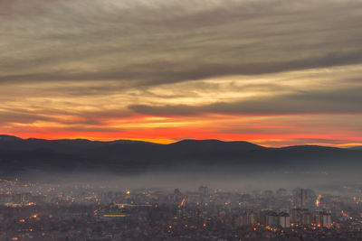 High angle view of illuminated city against sky during sunset