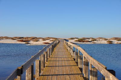 Pier over sea against clear blue sky