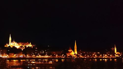 Illuminated bridge over river at night