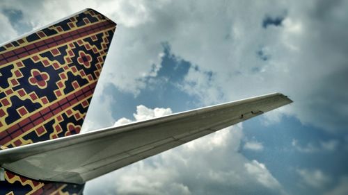 Low angle view of airplane wing against sky