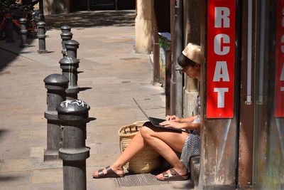 Woman sitting on street working on notebook