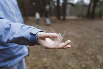 Boy's hand holding plastic waste in forest