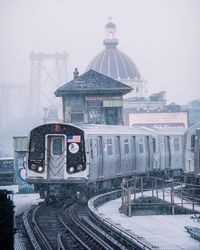 Train on railroad tracks in city against sky