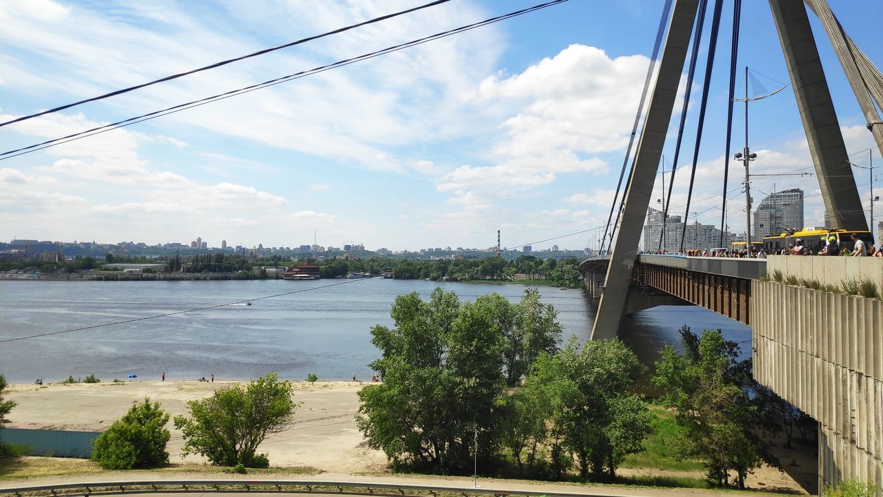 sky, transportation, cloud - sky, architecture, water, nature, built structure, plant, tree, day, connection, river, no people, bridge, bridge - man made structure, mode of transportation, city, cable, building exterior, outdoors, sailboat