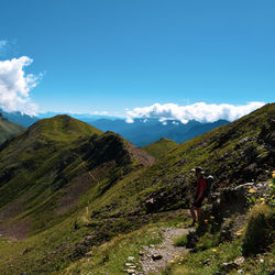 Rear view of man standing on mountain against sky