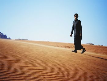 Full length of young man standing on sand dune