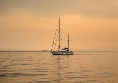 Sailboat sailing on sea against sky during sunset