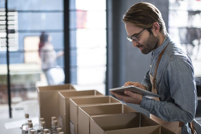 Man surrounded by cardboard boxes using digital tablet