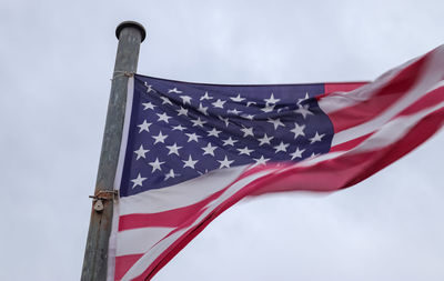 Usa flag at a flagpole moving in the wind against the sky