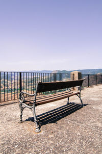 Benches on bench by sea against clear sky