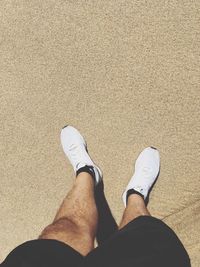 Low section of man standing on sand