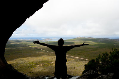 Rear view of man standing on landscape against sky