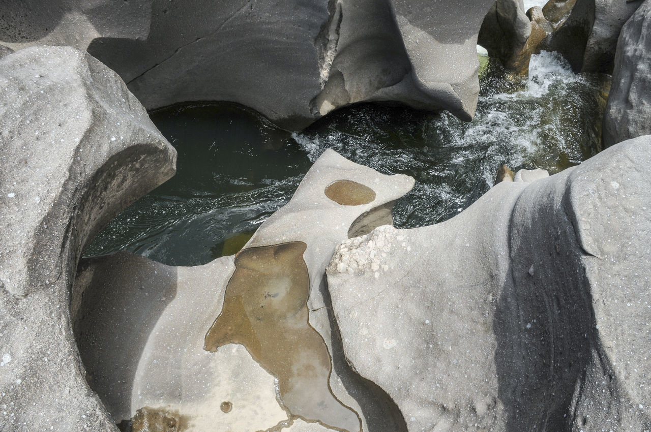 HIGH ANGLE VIEW OF ICE ON ROCKS AT SEA