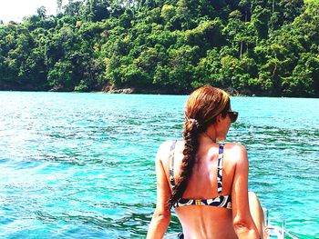 Rear view of young woman in bikini standing against sea