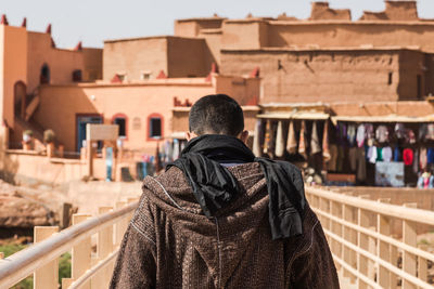 Rear view of man standing by railing against buildings